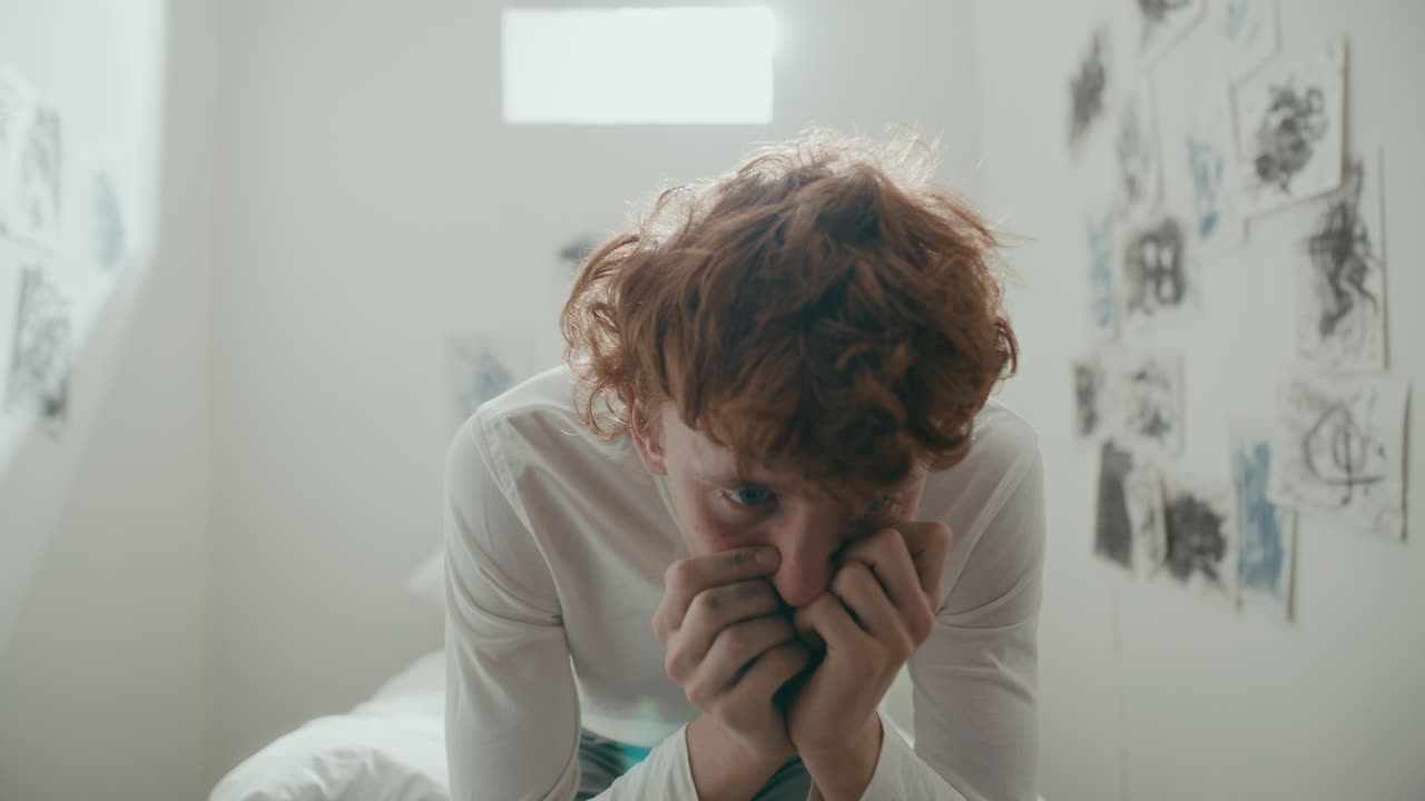 Anxious Male Patient Sitting on Bed in Psychiatric Ward