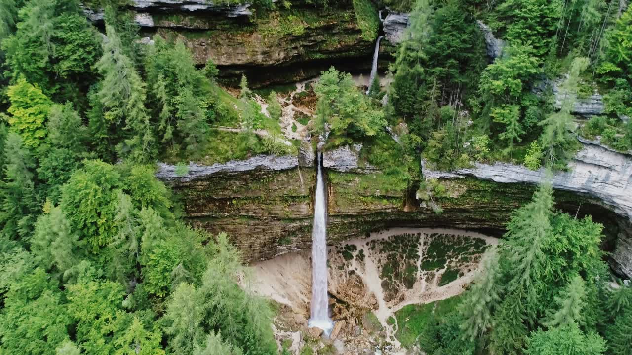 Drone flies through alpine trees revealing Pericnik waterfall, Mojstrana Slovenia