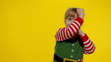 kid girl in christmas elf santa helper costume dancing, fooling around. new year holiday celebration