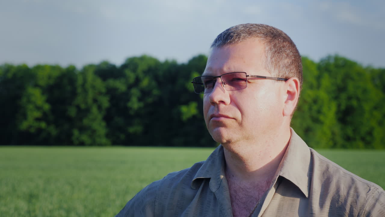 retrato de un granjero con gafas en el fondo de un campo verde 4k video