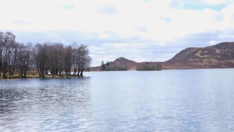 Vista-Panorámica-Del-Impresionante-Lago-Escocés-Con-árboles-Y-Terreno-Montañoso-En-Las-Tierras-Altas-De-Escocia,-Reino-Unido