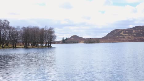 la vista panorámica del impresionante lago escocés de agua con árboles y terreno montañoso en las tierras altas de escocia, reino unido.