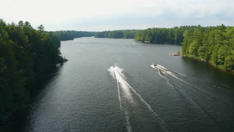 Jetskis-Und-Boote-Mit-Schlepprohren-Fahren-Nebeneinander-Auf-Einem-Fluss