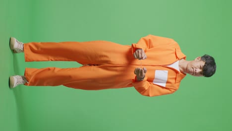 full body of asian male prisoner in handcuffs standing on the green screen background, shaking his head being upset on what he did