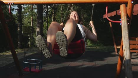 happy young woman on swing in children playground