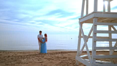 pareja embarazada playa. pareja de amor playa. pareja mirándose el uno al otro