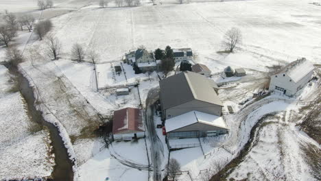 aerial shot of farm in beautiful snow covered rural area. shot in intercourse, pennsylvania in wintertime. a beautiful snow covered town with farms, meadows, farmlands and a small village center.