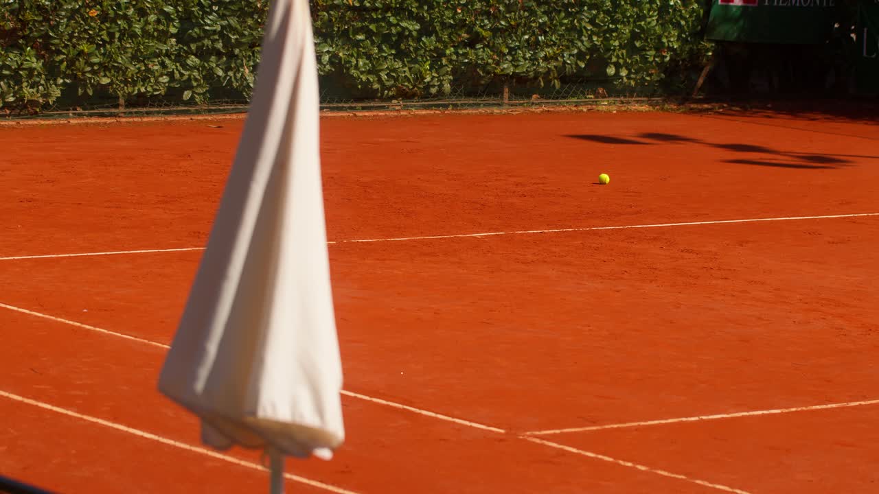 Static shot showing parts of a clay tennis court with a single tennis ball on the ground in Italy, Italia, capturing summer sports atmosphere