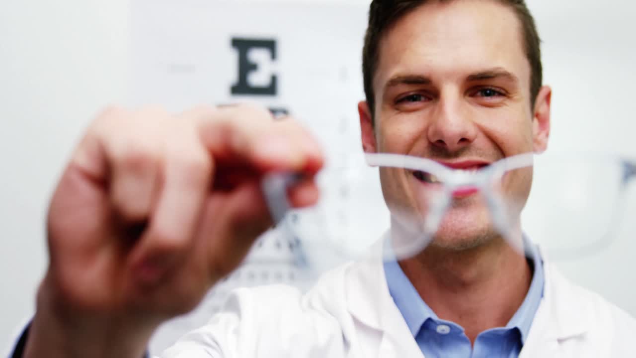 optometrista sonriente con gafas en la mano