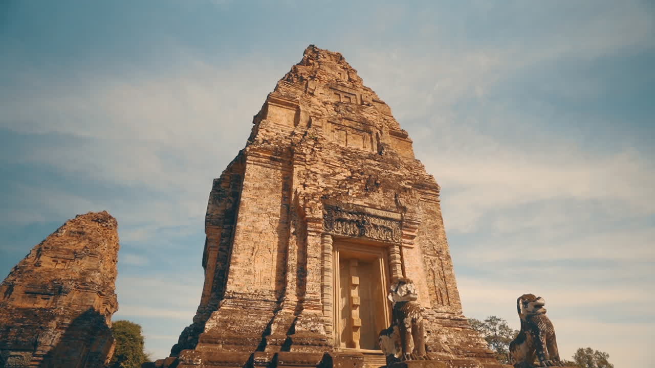 Golden light illuminating stone lion statues and tower of Hindu Pre Rup Temple, Angkor Cambodia