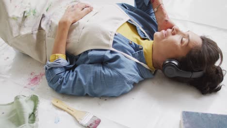 Video of biracial female artist in headphones resting in studio