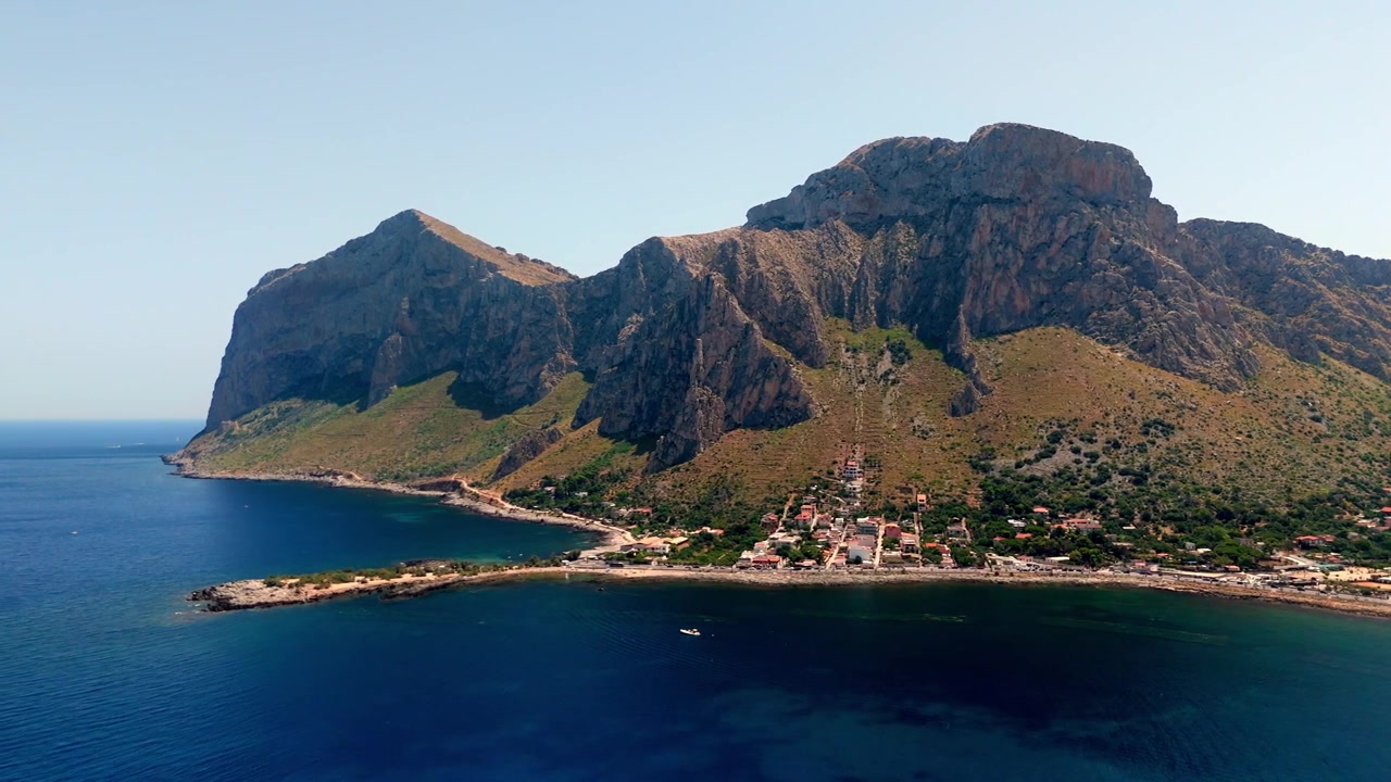 Góc nhìn từ trên cao vào ban ngày về khu bảo tồn thiên nhiên Capo Gallo ở Palermo, Sicily. Những ngọn núi hiểm trở tiếp giáp với bờ biển Địa Trung Hải hoang sơ dưới bầu trời trong xanh.