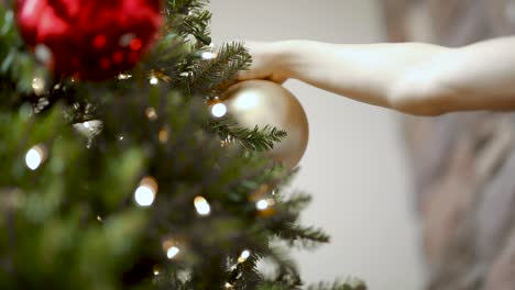 Person-hanging-bauble-decoration-on-Christmas-tree,-festive-winter-scene