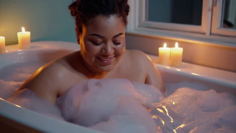 woman relaxing in a bubble bath with candles