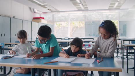 group of diverse primary school pupils drawing and writing on papers