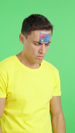 man with australian flag painted looking away with serious expression