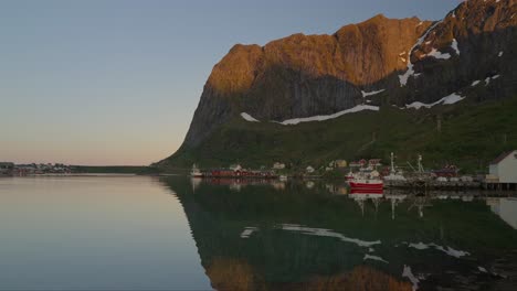 fishing village of reine with mountain reflections in lofoten at golden hour