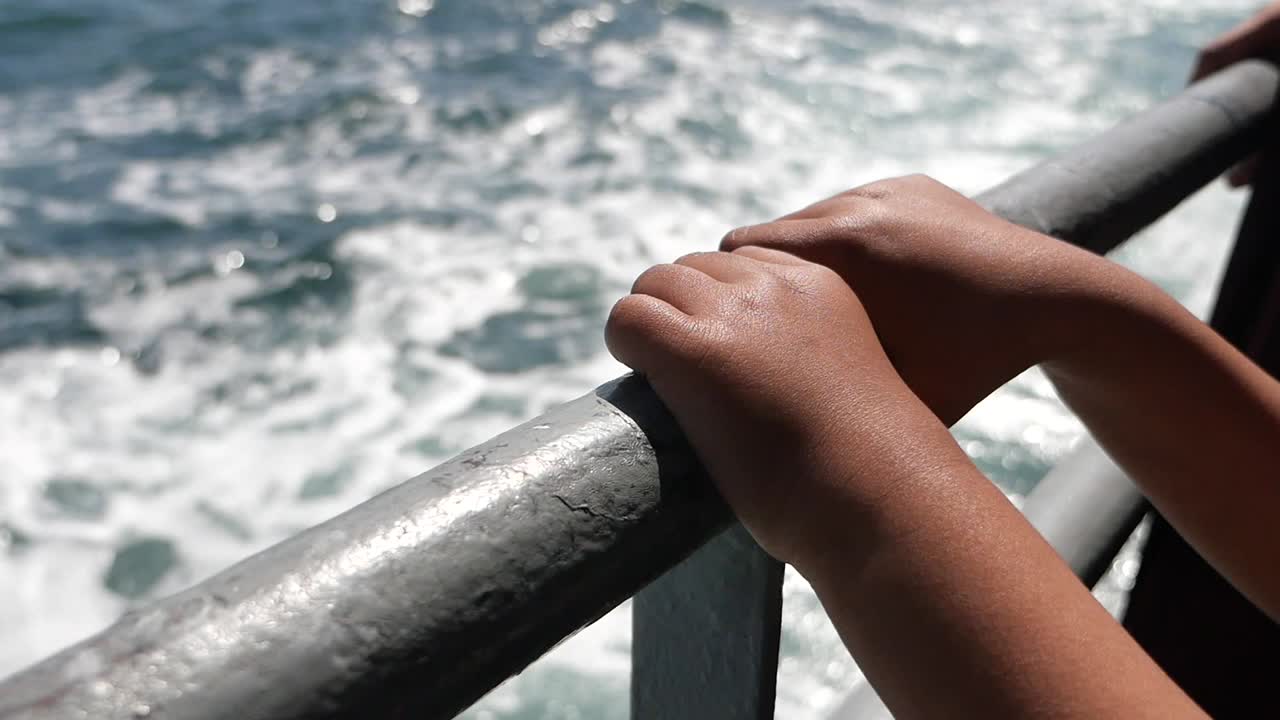 Hands on a railing overlooking the ocean