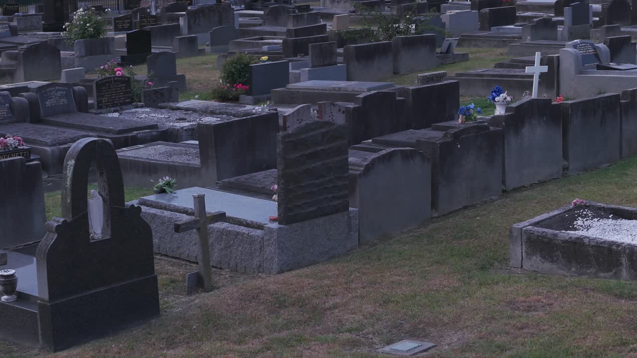Esplora un cimitero tranquillo a Ferntree Gully, Melbourne, durante l'ora d'oro. Questa scena serena immortala fiori, lapidi e il tenue sole al tramonto, senza persone presenti.