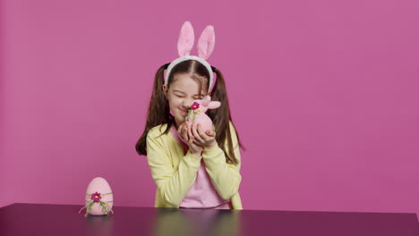 smiling toddler with bunny ears showing her handmade easter ornaments