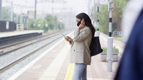 Geschäftspendler-Auf-Dem-Bahnsteig-Mit-Mobiltelefonen,-Die-Während-Einer-Pandemie-PSA-Gesichtsmasken-Tragen