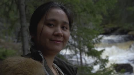 smiling girl in the forest besides a river