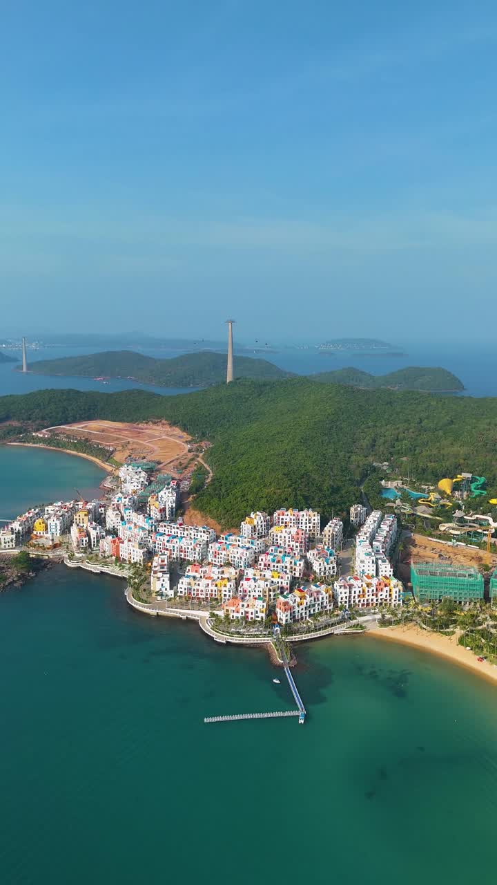 Vertical high-altitude and wide-angle drone shot of the VinHomes construction site on Phu Quoc Island, Vietnam. A luxury resort designed with Santorini-style architecture.