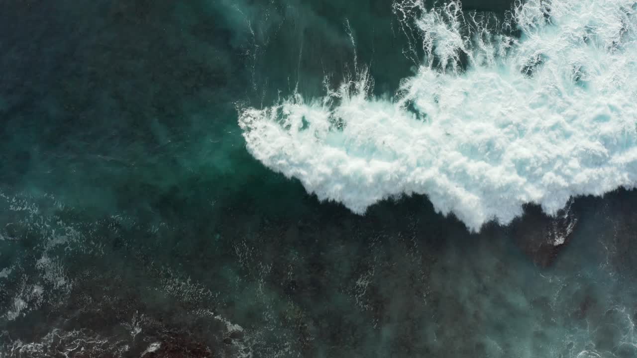 Beautiful aerial top down view of clear turquoise blue ocean water covering reef rocks