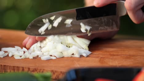 Young-man-chops-onions-on-a-wooden-board-in-his-garden-close-up