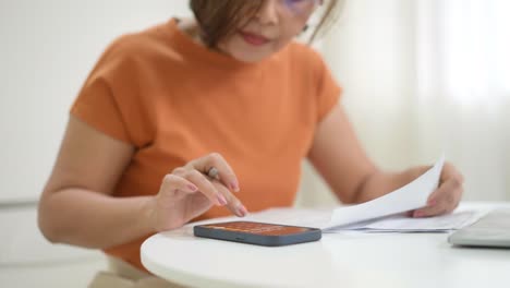 asian woman calculating bills at home