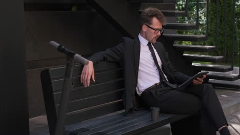 businessman reading tablet on a bench