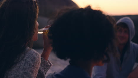 fogata en la playa con un grupo de amigos, bebiendo cerveza y tocando la guitarra