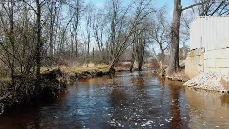 reenvío de drones aéreos sobre un canal de agua con bosque en un lado y casas en otros lados en la ciudad de mishicot, condado de manitowoc, centro este de wisconsin, estados unidos durante el día