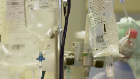 several intravenous fluid bags hanging on the intravenous pole next to oxygen tank in a patient's room in the hospital