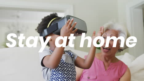 animation of stay at home text over african american grandmother and granddaughter using vr headset