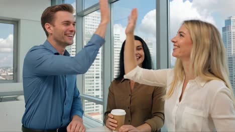 colleagues high-fiving in modern office with city view