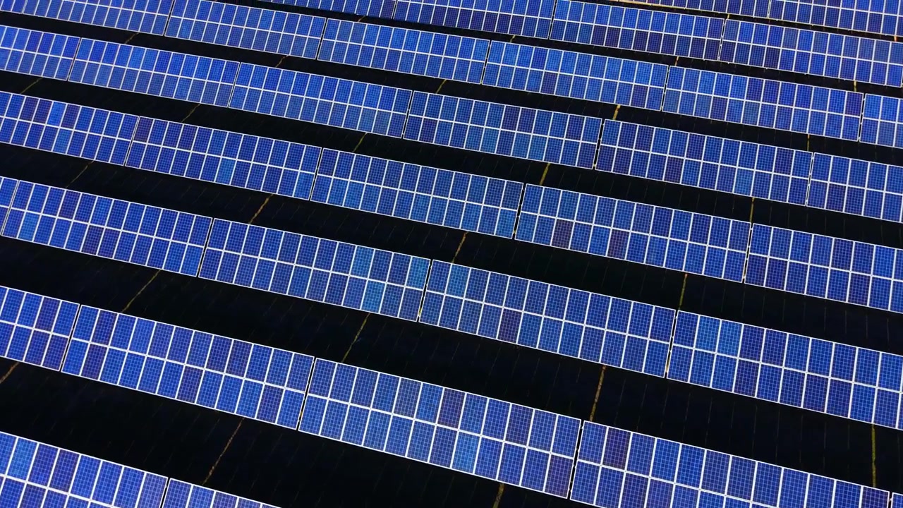 Centinaia di pannelli solari blu scuro riempiono l'inquadratura da bordo a bordo in un motivo astratto diagonale. Fitte file di moduli fotovoltaici che riempiono l'intera inquadratura, Bulgaria.