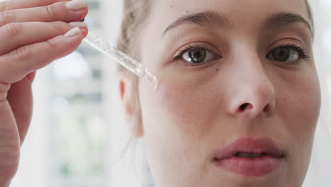 Mujer-Birracial-Aplicando-Aceite-Facial-En-El-Baño,-Cámara-Lenta