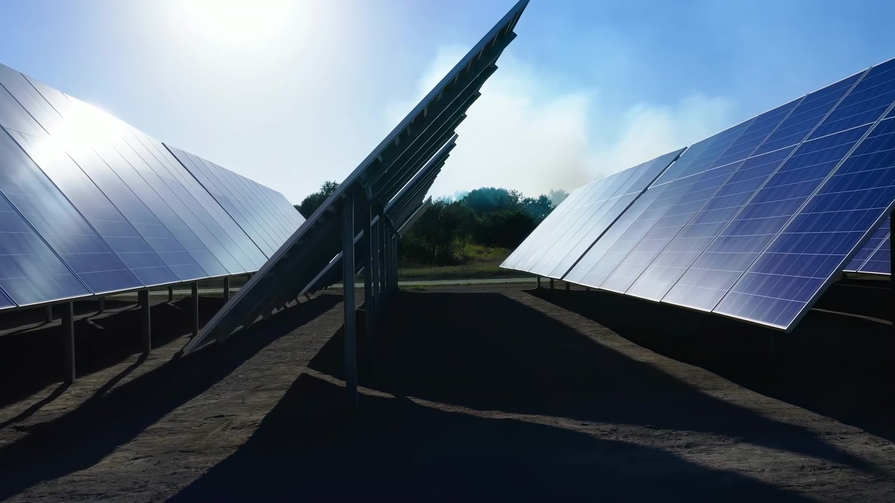 Al centro della sequenza, file di pannelli solari si inclinano verso l'alto in direzione del sole, creando linee diagonali tra le cornici metalliche.