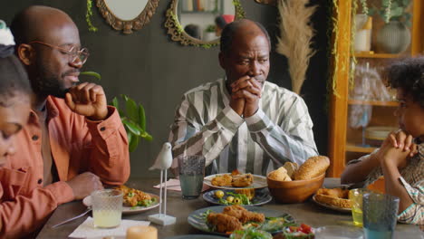 african american family praying before eating at home