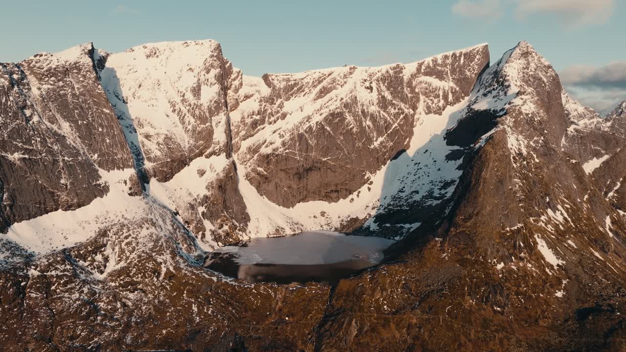 Snow-dusted Rugged Mountains With Still Lake Near Reinebringen In Reine, Norway. drone shot