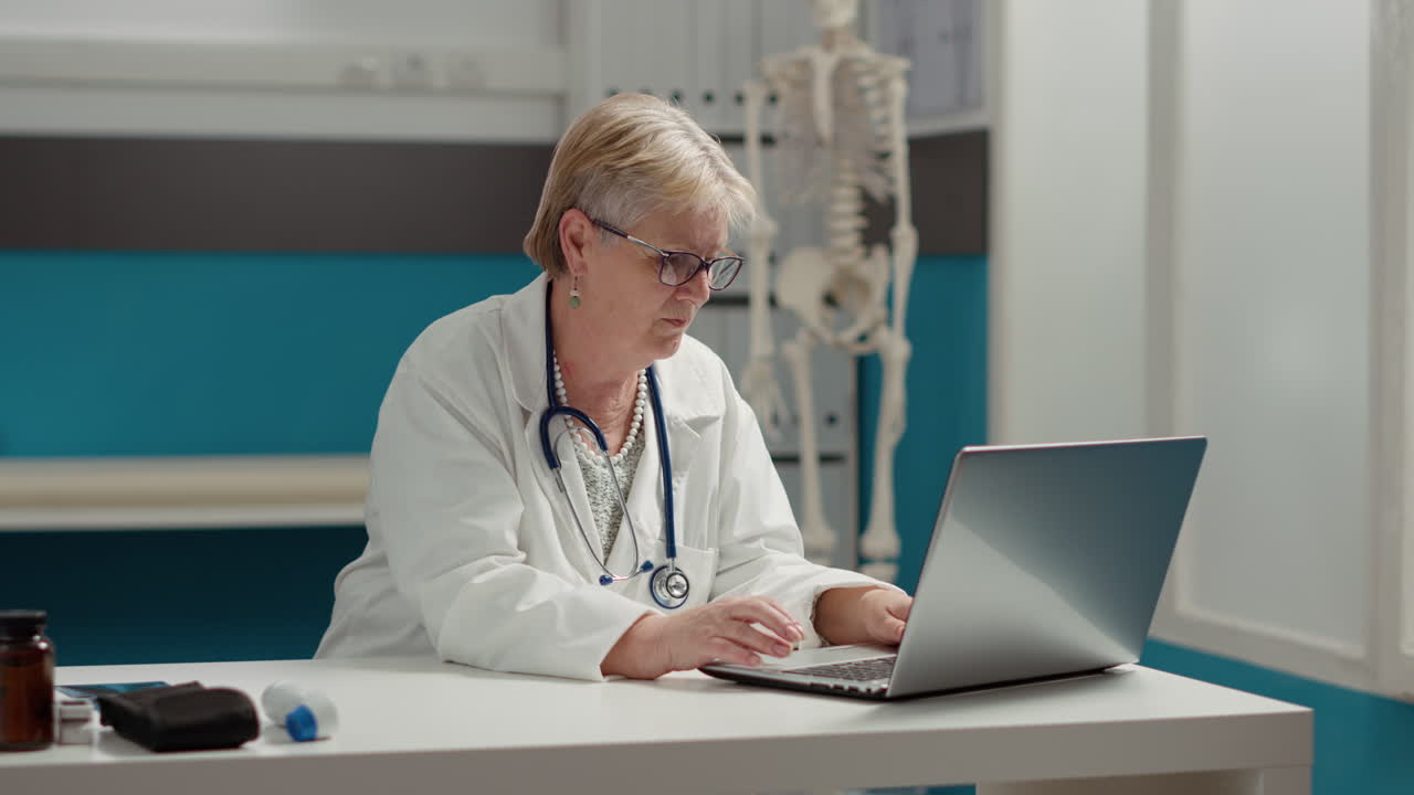 Portrait of general practitioner working on laptop in medical office