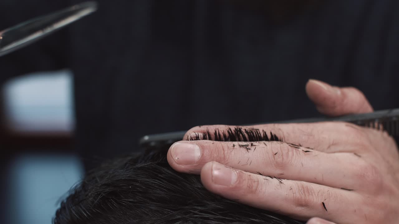 Nærbillede af en barber, der klipper hår med saks og en kam