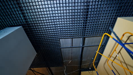 dark ceiling with grate in the spacious premise. unfinished room with air conditioner and wires. low angle view.