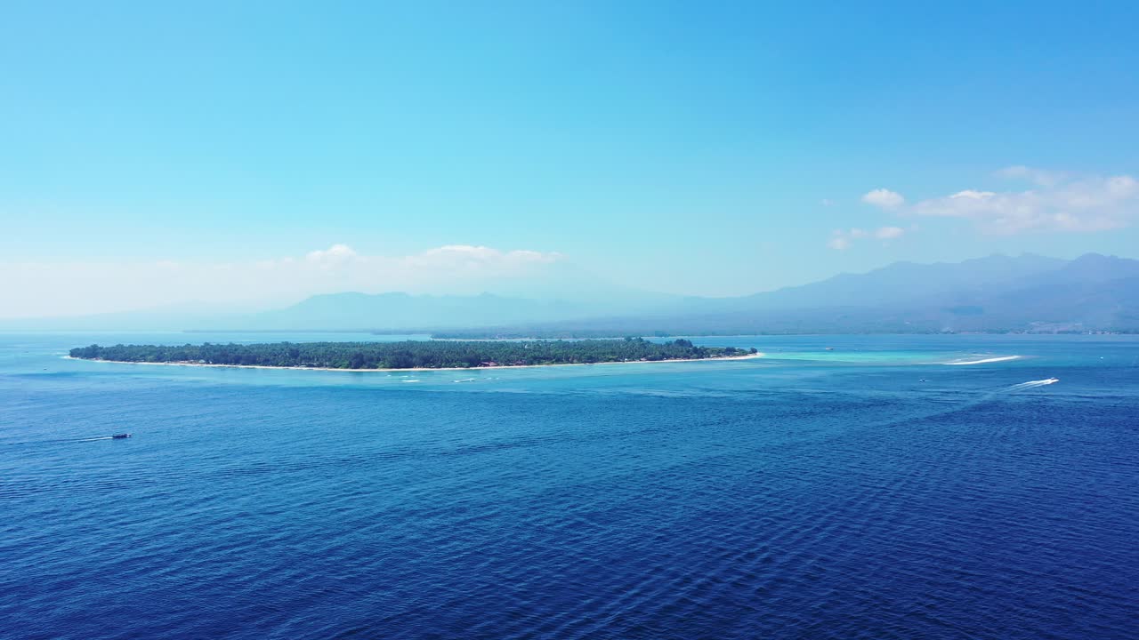 밝고 맑은 하늘 아래 보트가 추적하는 푸른 푸른 바다로 둘러싸인 발리의 무성한 초목이 있는 저지대 열대 섬