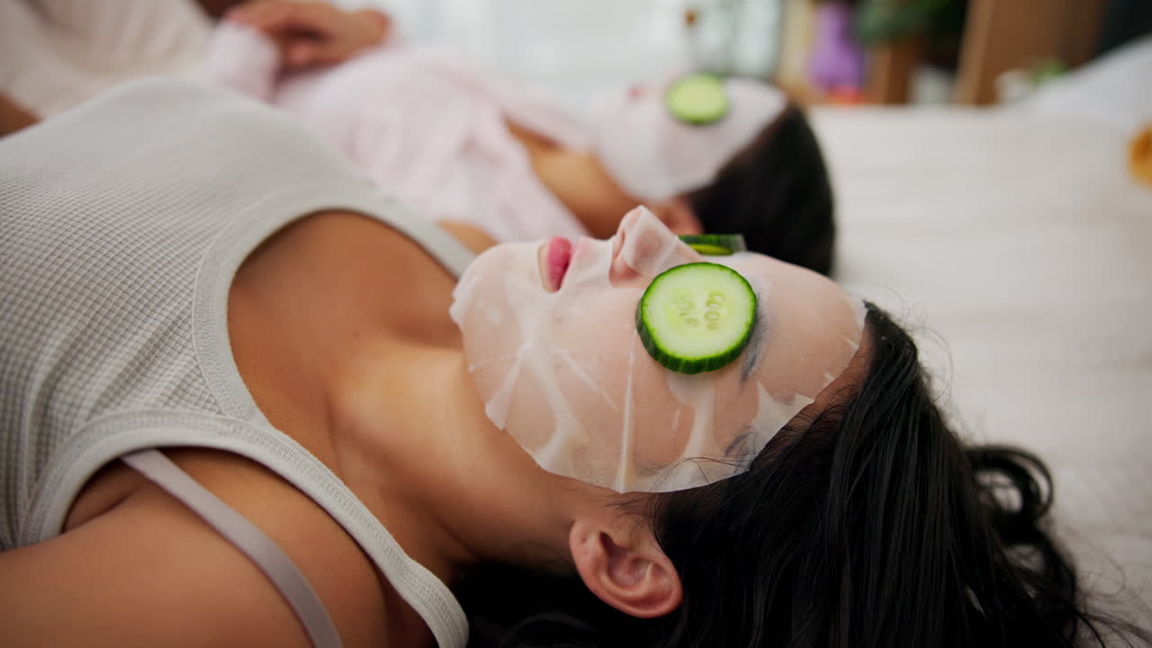 Women relaxing with facial masks and cucumber slices