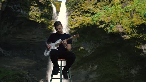 man playing guitar in front of a beautiful waterfall in iceland-11