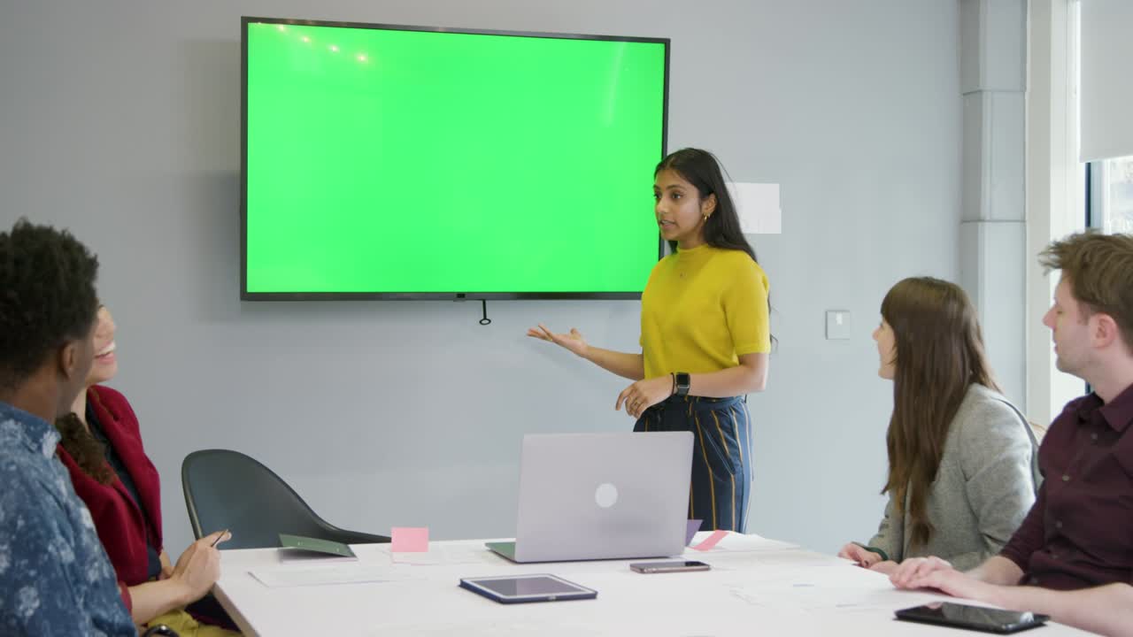 mujer presentando a colegas de negocios usando pantalla verde
