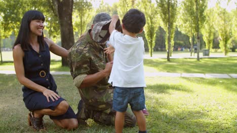 happy dad wearing military uniform, having fun with his wife and kids at the park