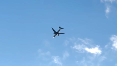 bottom up tracking shot of flying airplane against blue sky landing in amsterdam airport - slow motion 4k